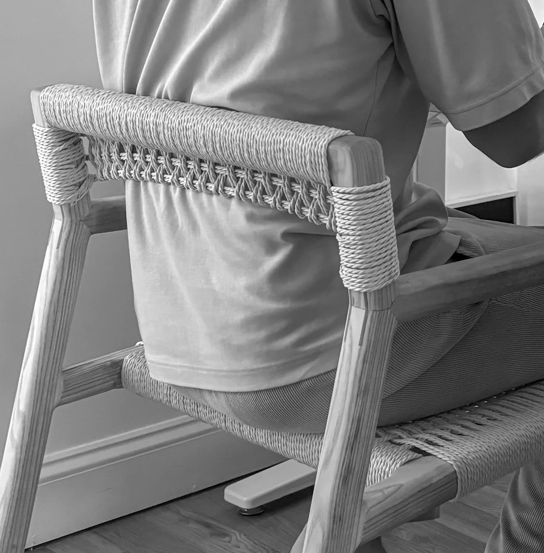 Close-up detail of a wooden chair back with woven rope wrapping and lashed joinery against a neutral background by Good Chair Co.