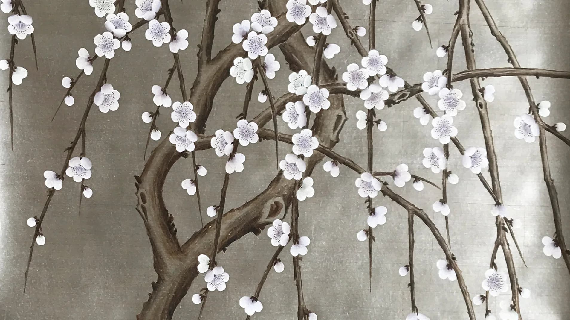 Minimalist floral installation featuring delicate white blossoms on natural branches against a neutral wall, creating an elegant botanical interior design by Gracie.