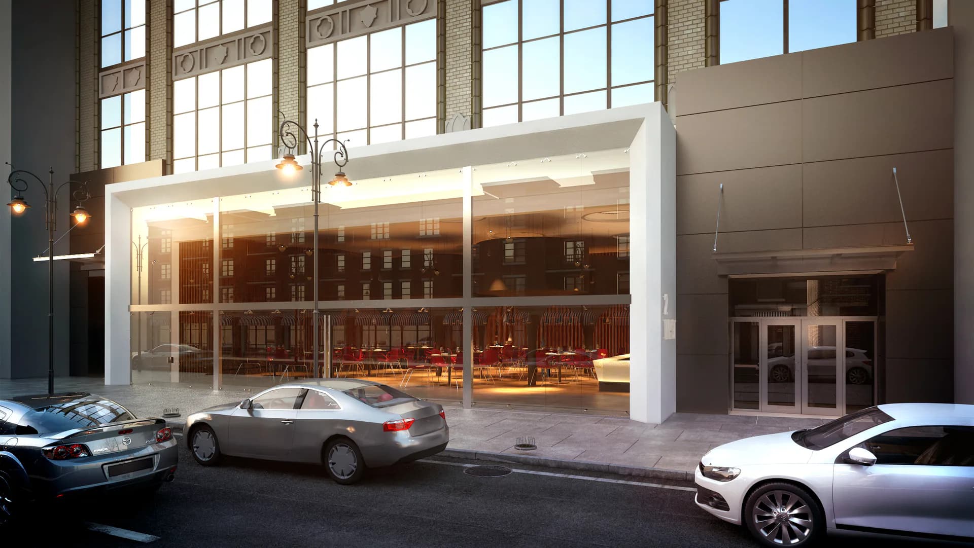 Modern storefront with floor-to-ceiling windows, warm interior lighting, brick facade, and street-level cars parked outside by Gregory Switzer Architecture.