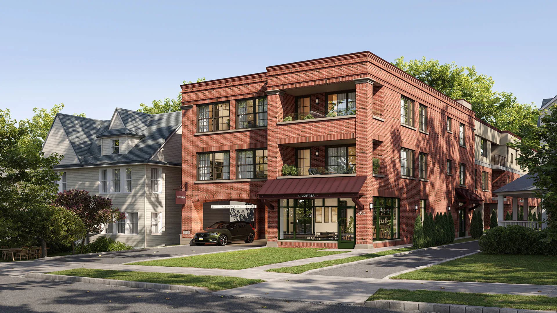 Red brick corner building with green-trimmed windows, ground-floor storefront, and manicured lawn by Gregory Switzer Architecture.