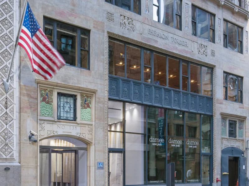Renovated historic commercial building facade with stone exterior, large storefront windows, and American flag, designed by GRT Architects.