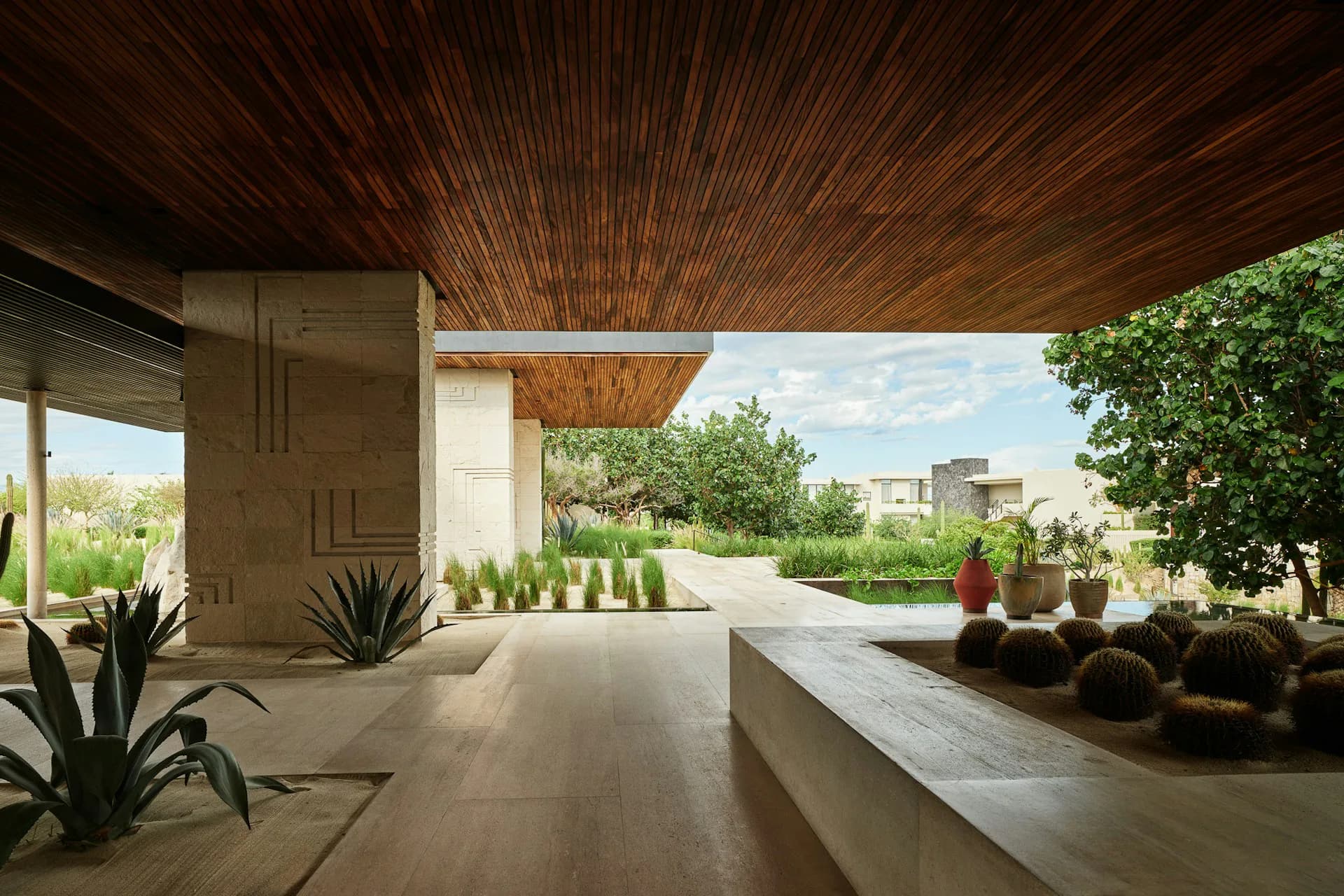 Modern residential terrace with wooden ceiling, concrete floors, and desert landscaping overlooking a cityscape by Guerin Glass Architects.