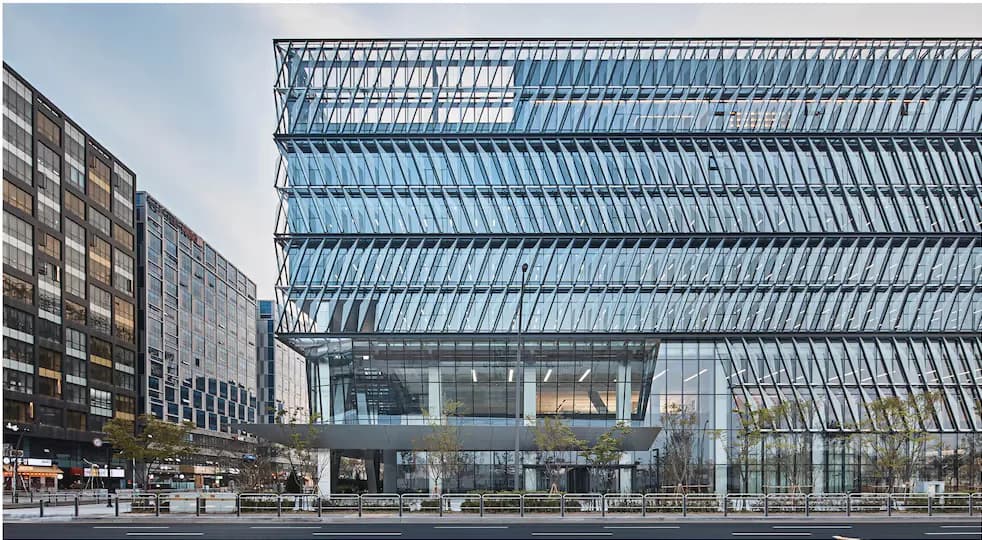 Modern glass and steel commercial building facade with geometric latticed exterior framework and large glazed surfaces, designed by H ARCHITECTURE.