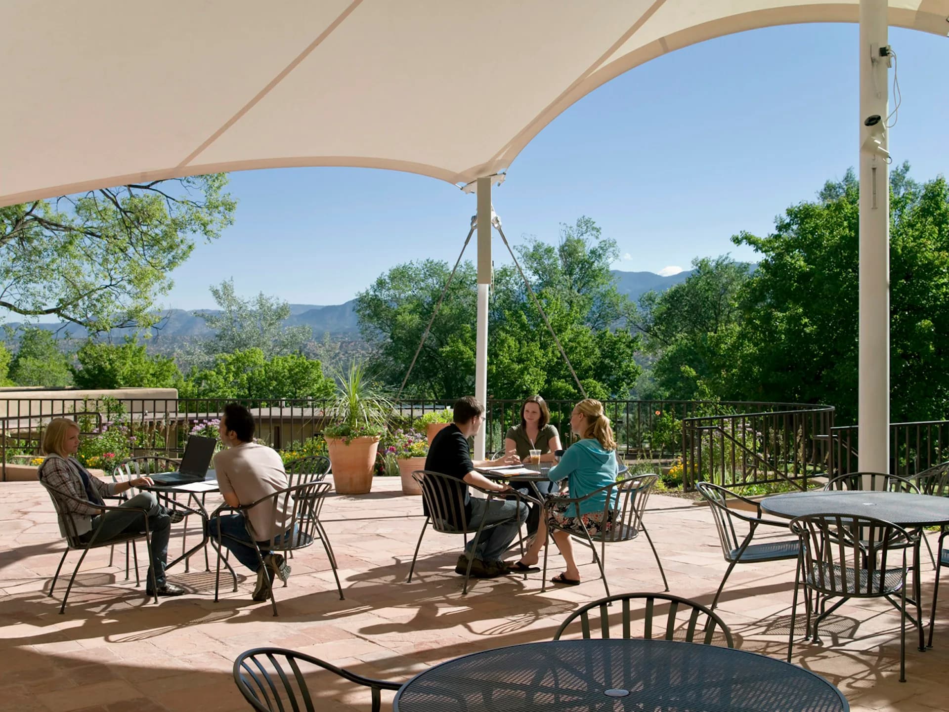 Expansive outdoor terrace with cream canvas shade structures, metal furniture, and panoramic mountain views, designed by H3 Hardy Collaboration Architecture, LLC.