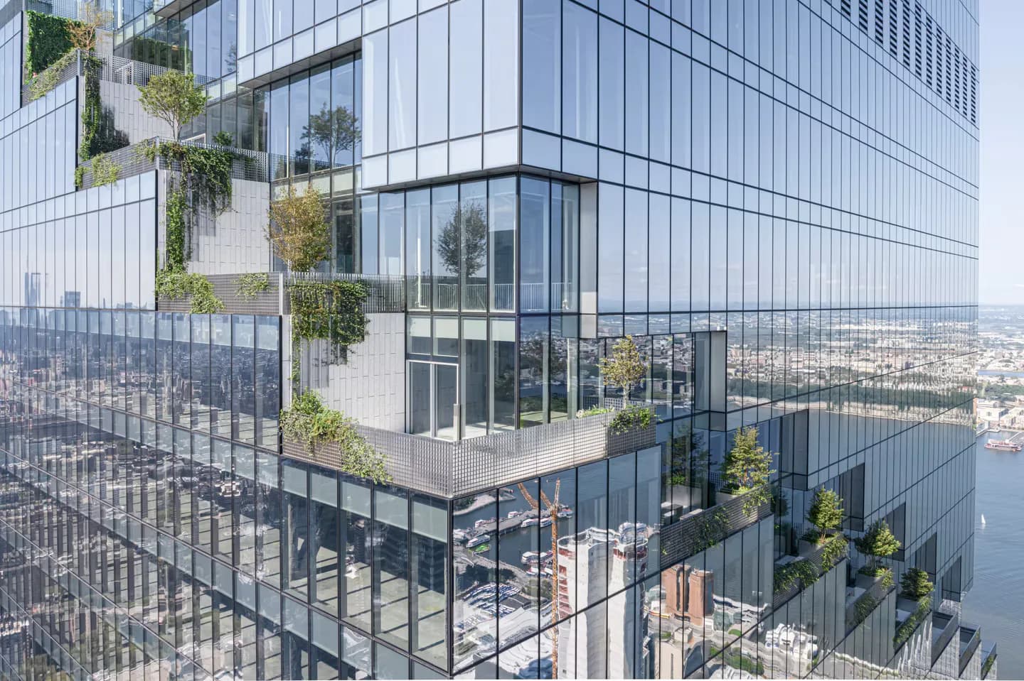 Modern high-rise building exterior with glass curtain wall, integrated green planters, and expansive city skyline view, designed by Heintges Consulting Architects & Engineers P.C.
