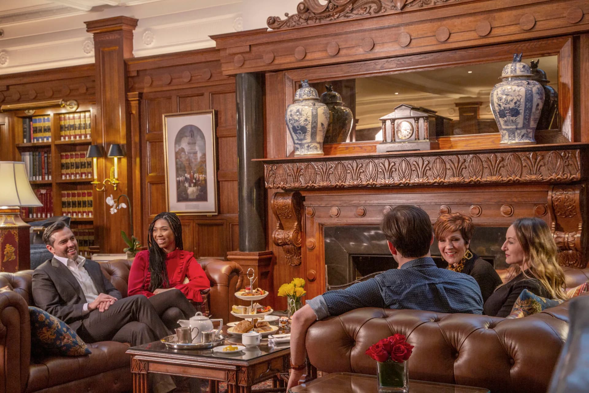 Elegant wood-paneled living room with leather seating, decorative Asian porcelain on mantlepiece shelves, and warm traditional furnishings by Helpern Architects.