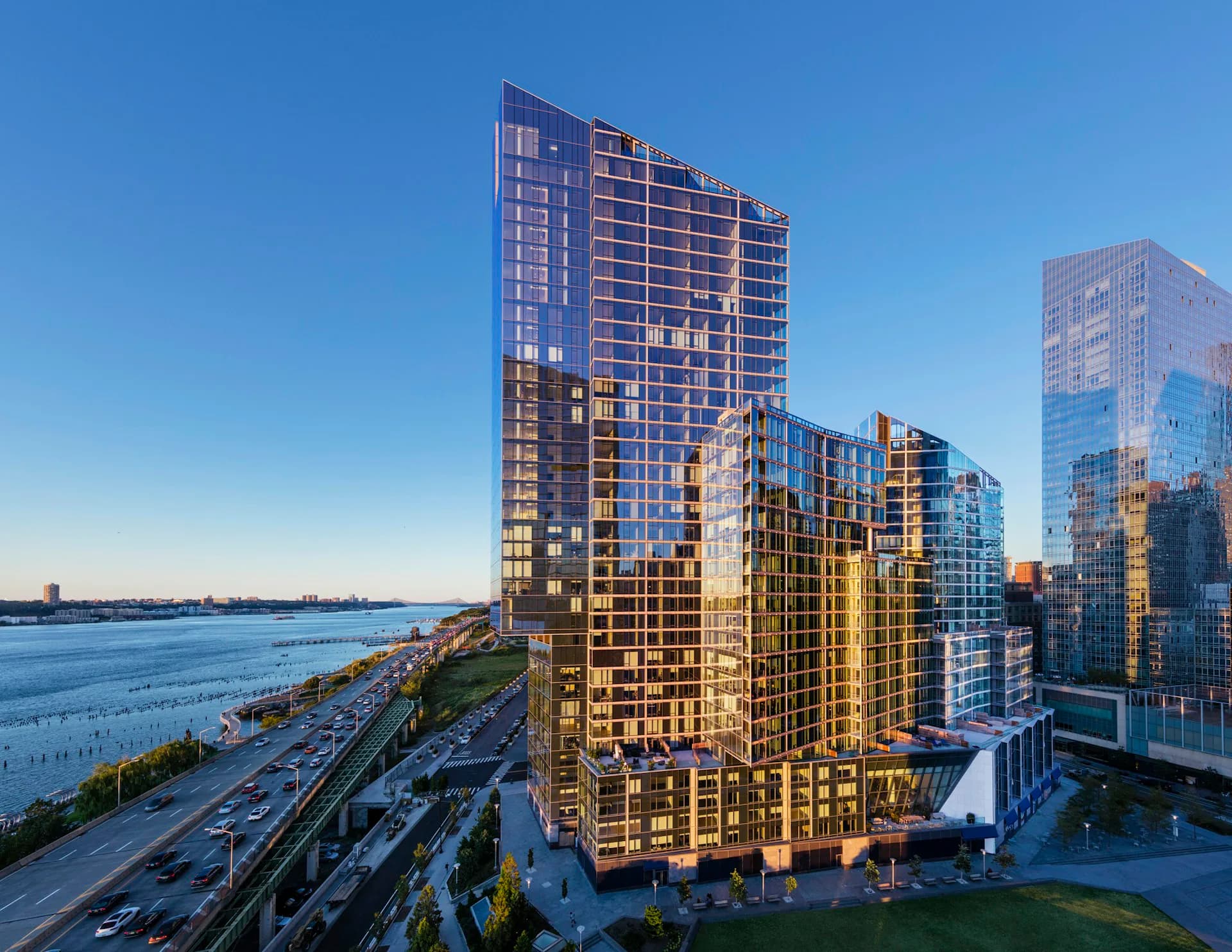 Waterfront residential towers with warm golden and cool blue glass facades overlooking the water, designed by Hill West Architects.