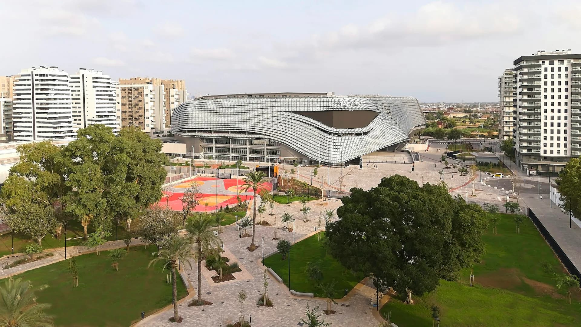 Modern curved architecture museum building with red plaza, surrounding parks and residential towers in urban landscape by HOK.