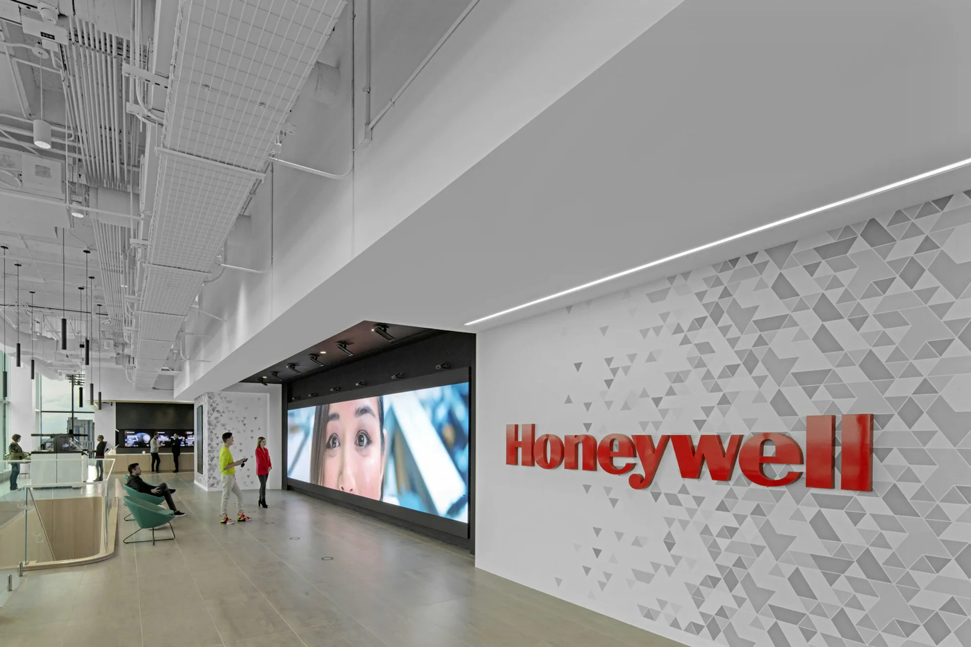 Modern corporate lobby featuring geometric patterned wall with red Honeywell signage, minimalist lighting, and polished flooring by HOK.