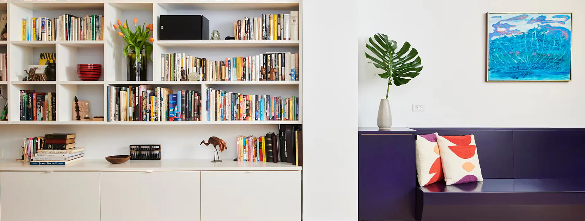 Modern living room with white built-in shelving unit filled with books and decor, dark blue sofa with cushions, potted plant, and framed artwork by Hub Woodworks.