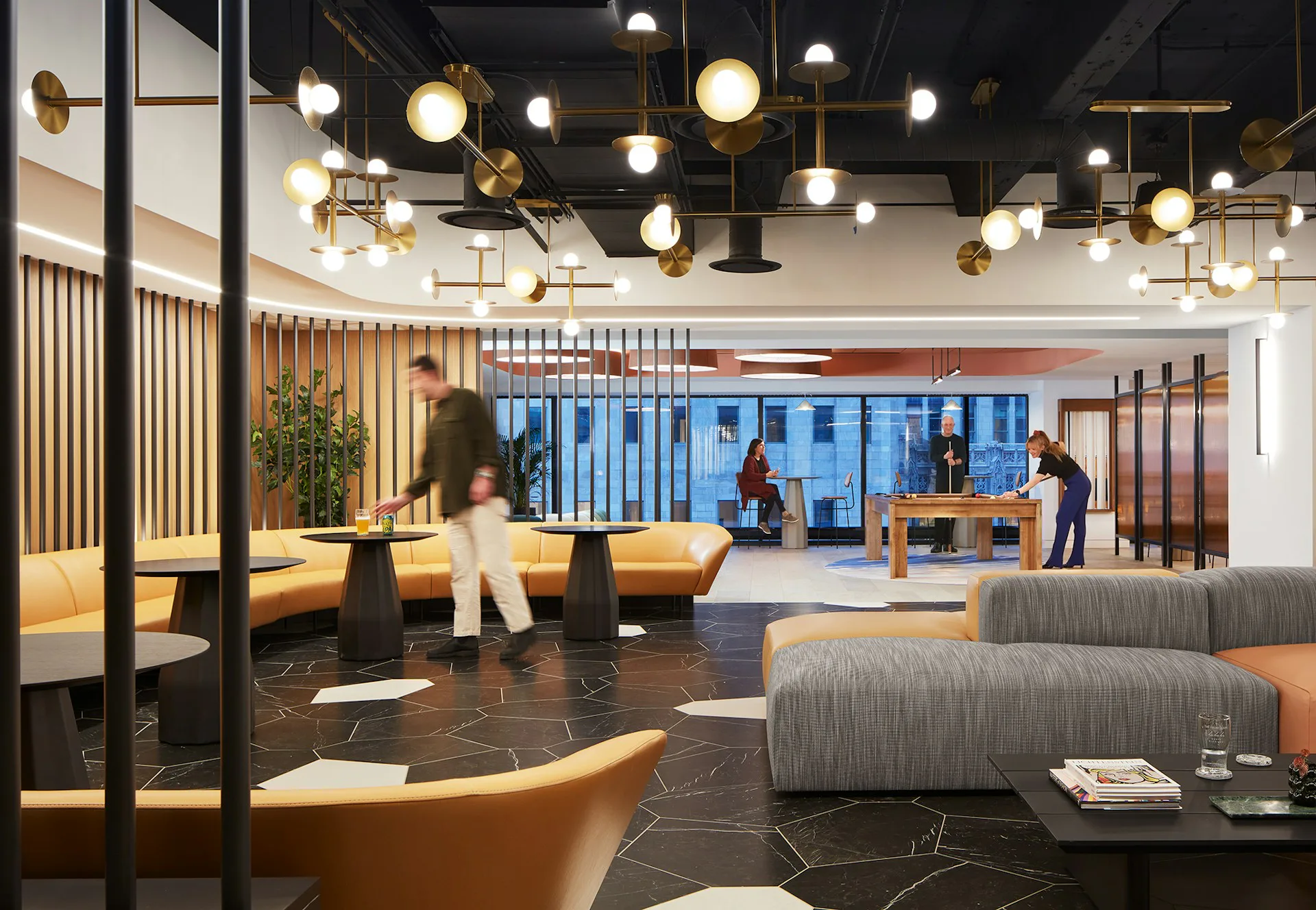Modern corporate lounge with curved seating, pendant lighting fixtures, and floor-to-ceiling windows overlooking a cityscape, designed by Huntsman Architectural Group.