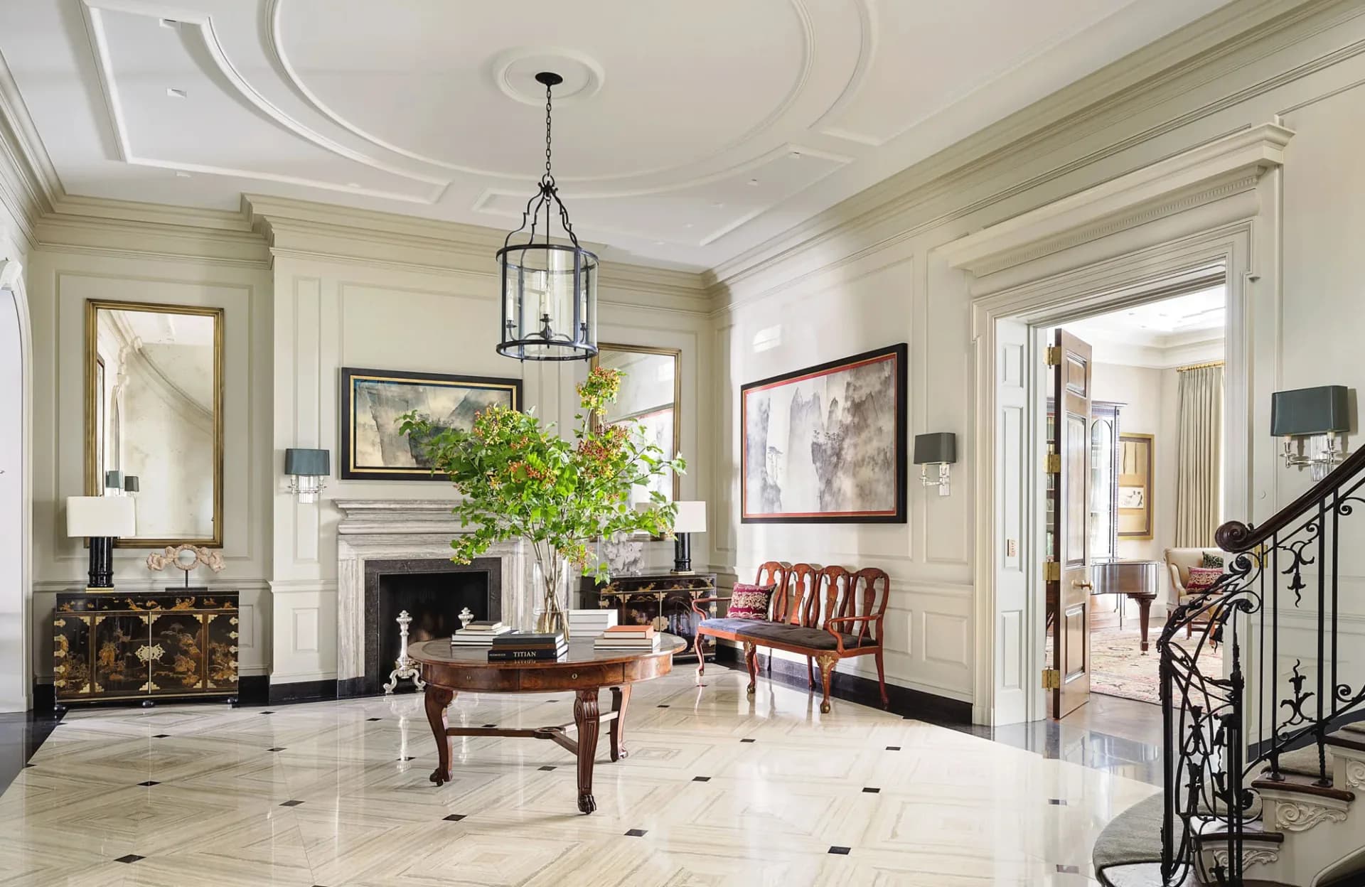 Elegant foyer with white marble flooring, classical fireplace, coffered ceiling, and ornate mouldings by Hyde Park Mouldings.