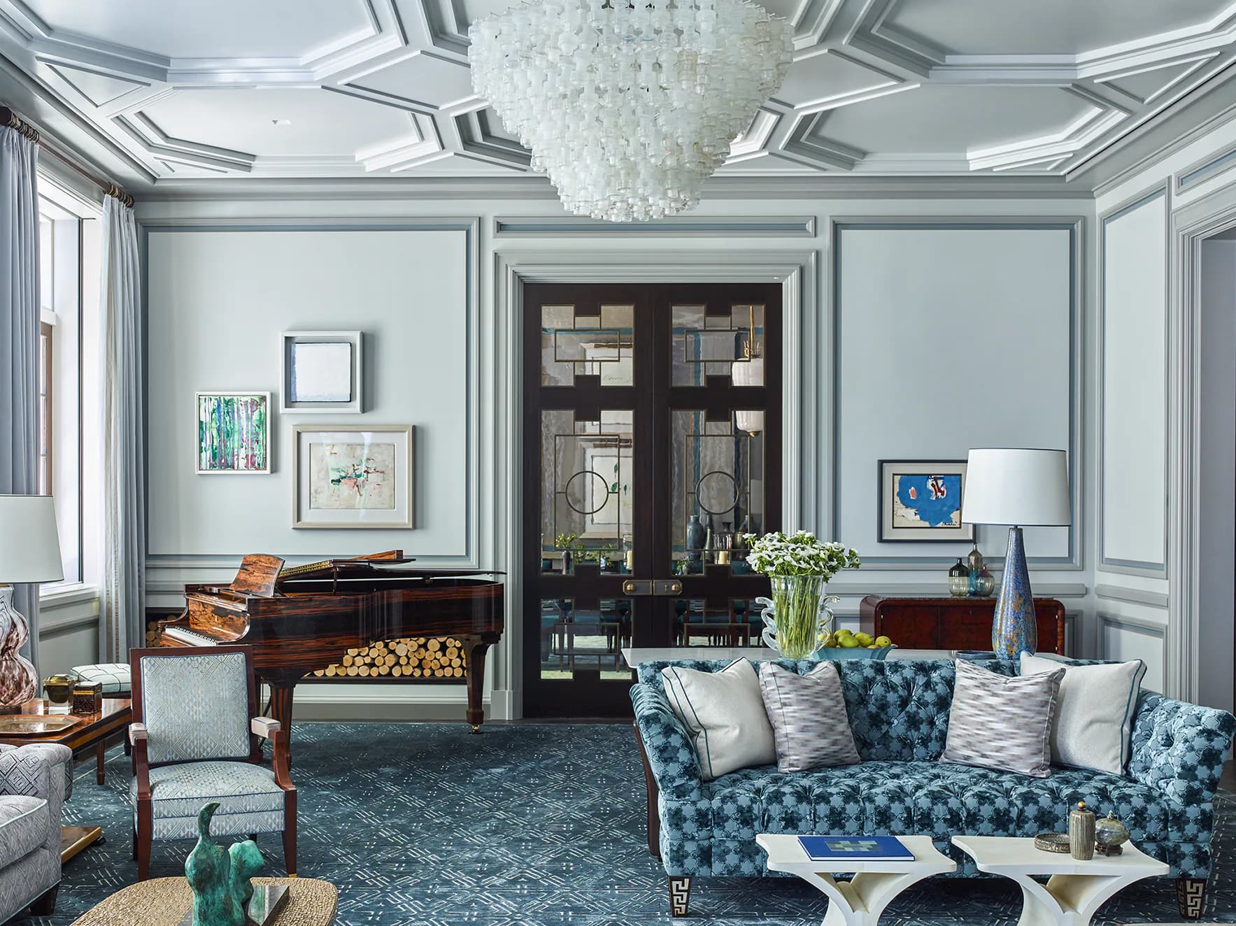 Elegant living room with coffered ceiling, patterned blue sofa, grand piano, and dark wood cabinetry by Hyde Park Mouldings.