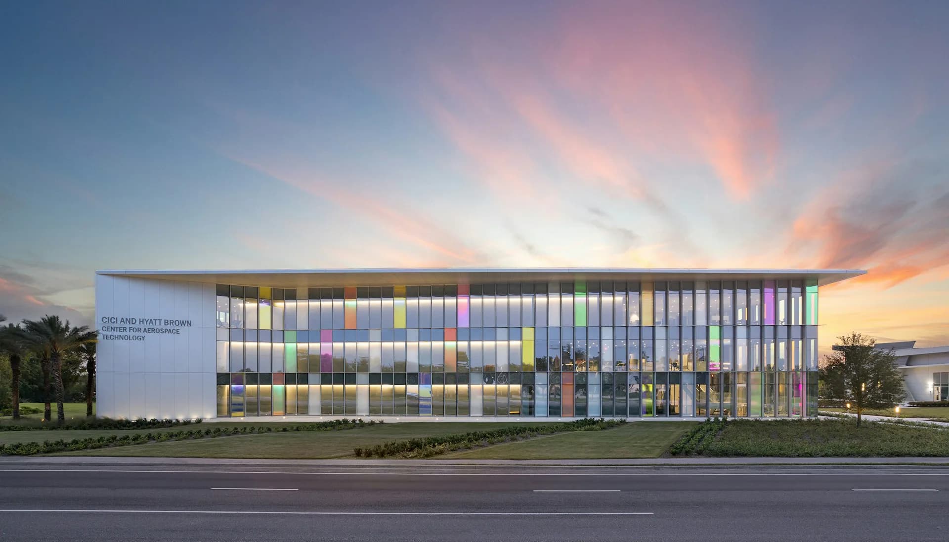 Modern institutional building with glass facade and warm interior lighting at dusk, designed by ikon.5 architects.