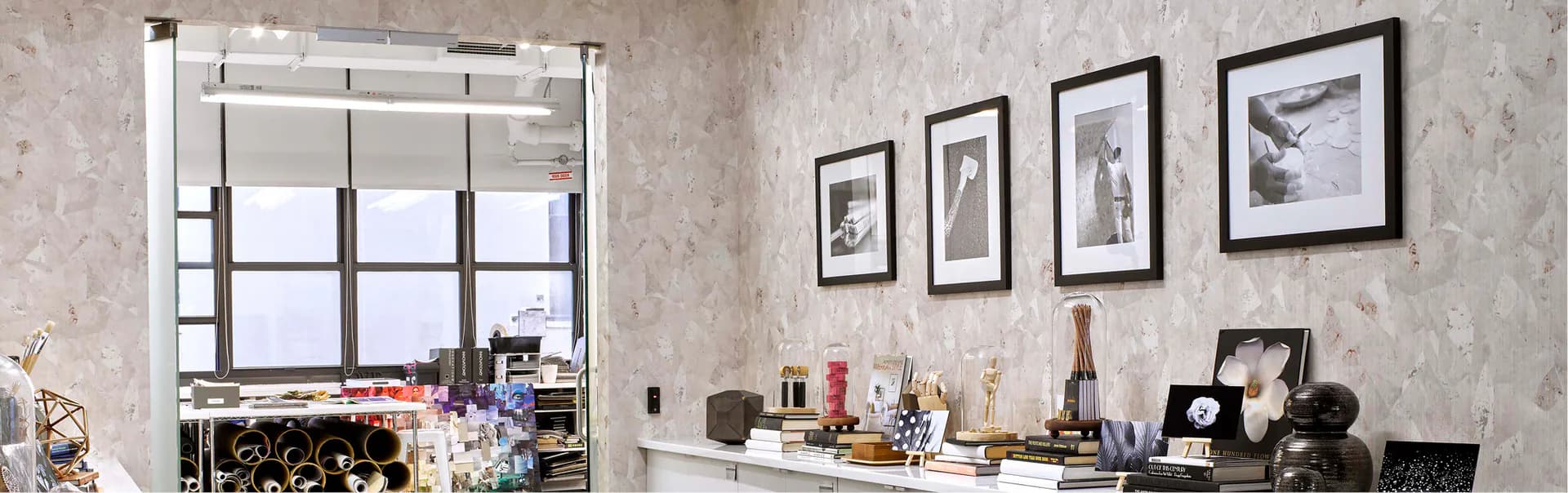 Modern home office with textured wallcovering, white gridded windows, floating desk, black accessories, and framed artwork by Innovations in Wallcoverings.
