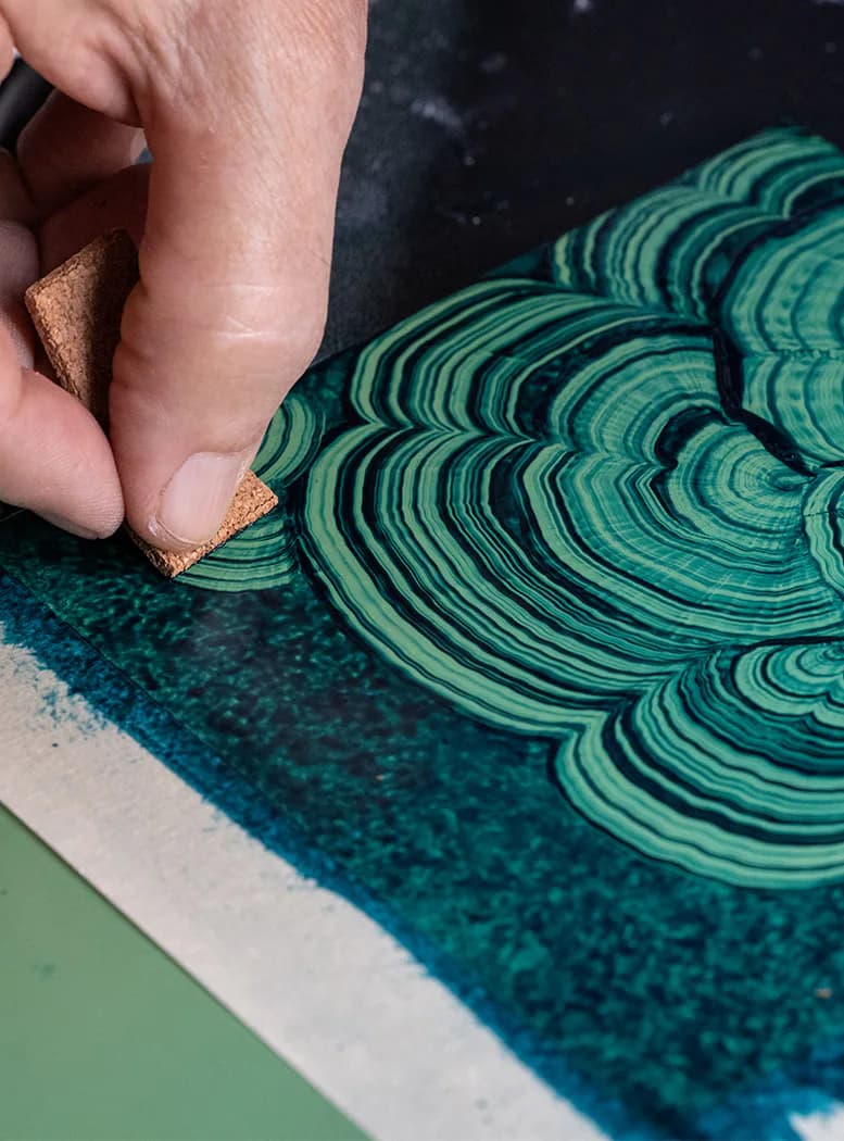 Hand holding a cork detail beside green and teal striped curved sculptural form with layered patterns by Isabel O'Neil Studio Workshop.