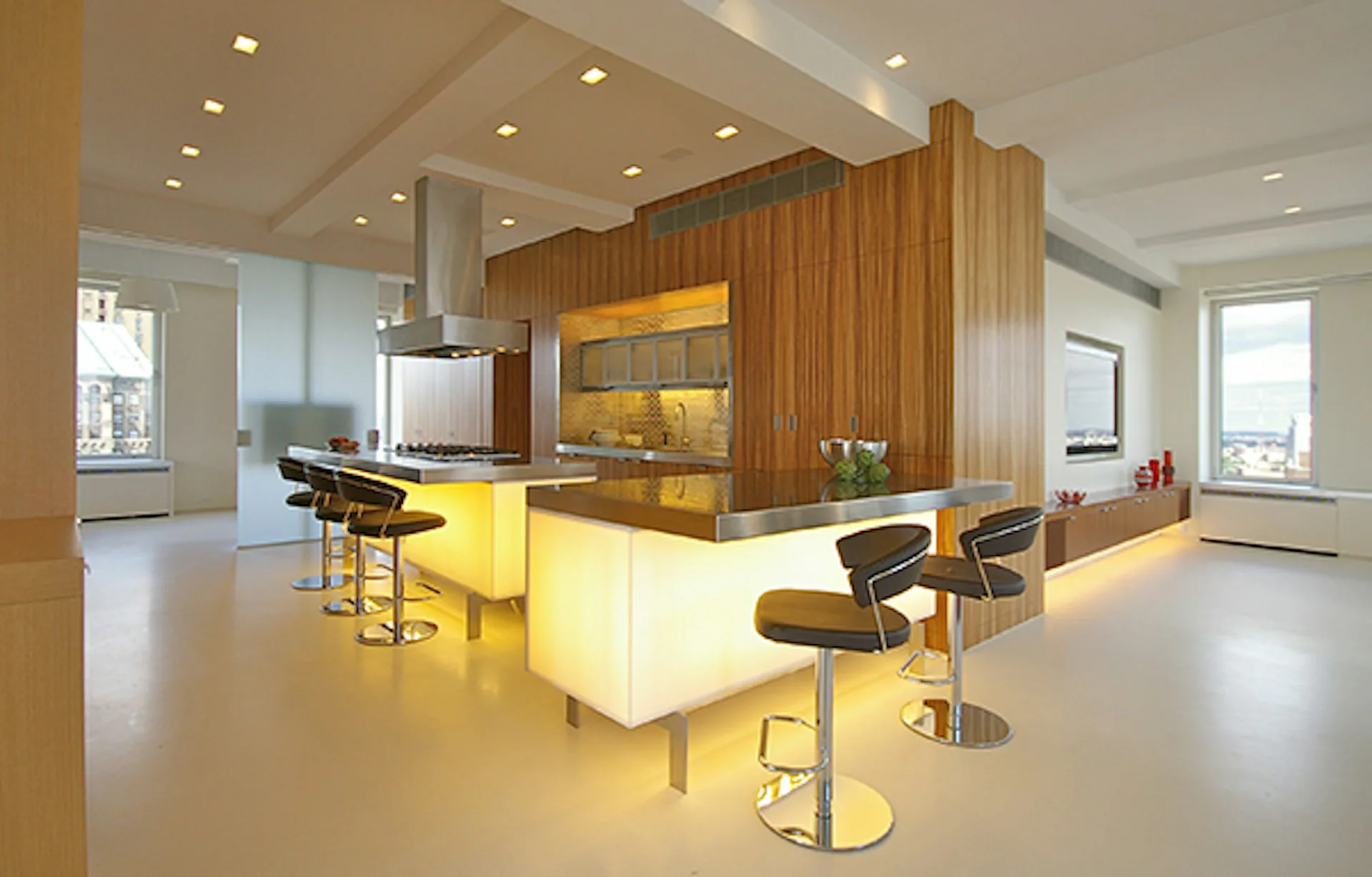 Modern kitchen with yellow-white island, wood-paneled accent wall, and bar seating, designed by James Koster Architect, PLLC.