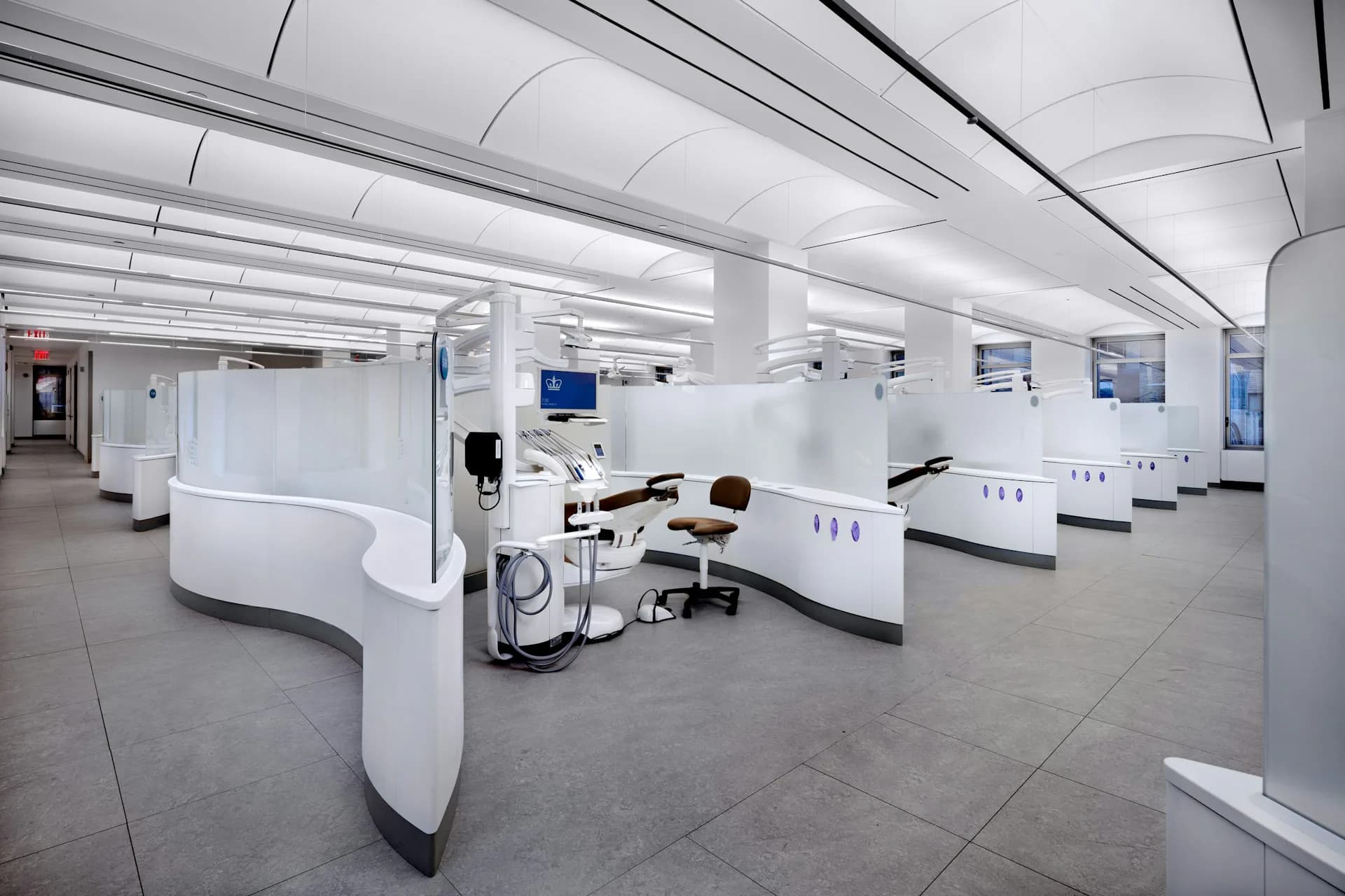 Bright medical laboratory with modular white workstations, overhead linear lighting, and polished concrete flooring designed by Jeffrey Berman Architect.