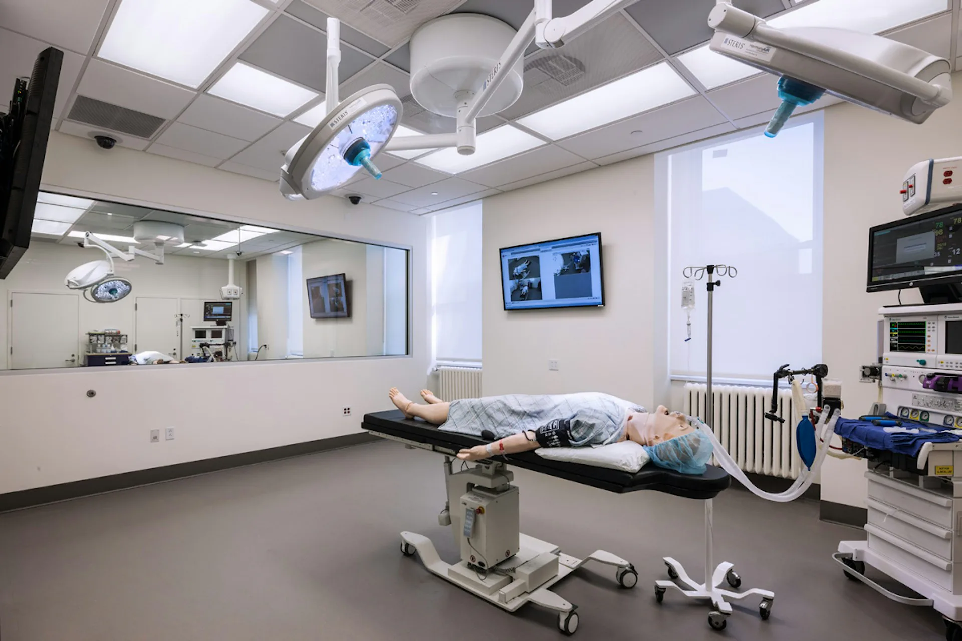 Modern surgical operating room with bright overhead lighting, medical equipment, and sterile white walls and flooring by Jeffrey Berman Architect.