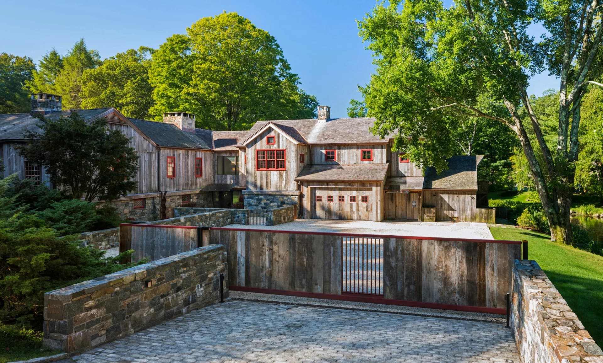Exterior view of a traditional stone and brick residence with manicured grounds and gated driveway by Joeb Moore & Partners.