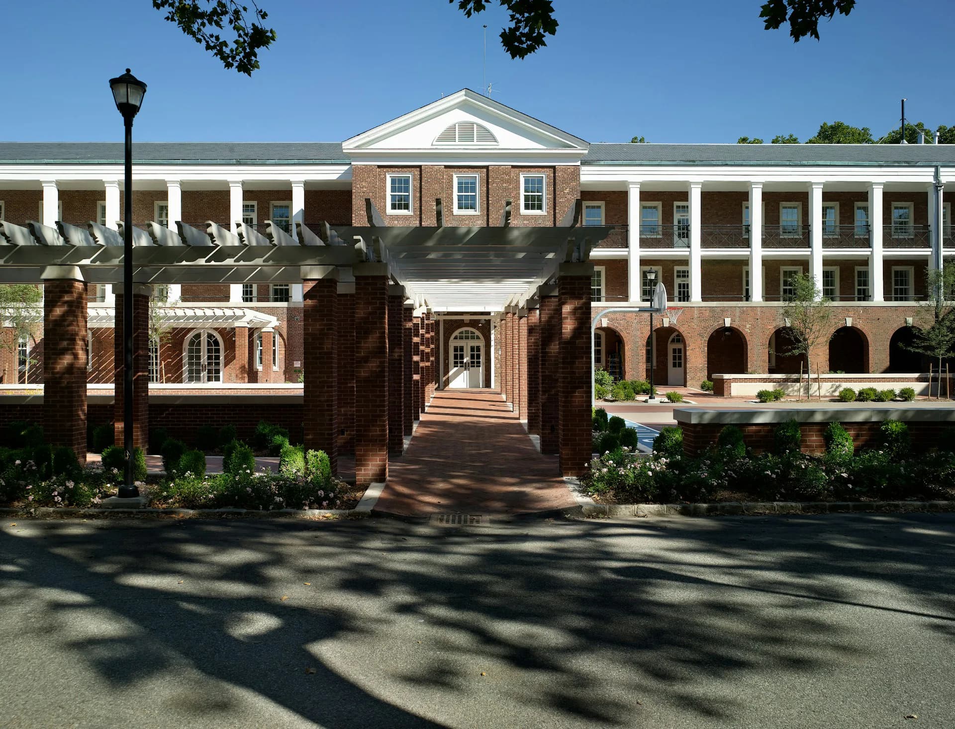 Brick and stone academic building with classical white columns, arched entrances, and manicured landscaping, designed by Ciardullo A&E.