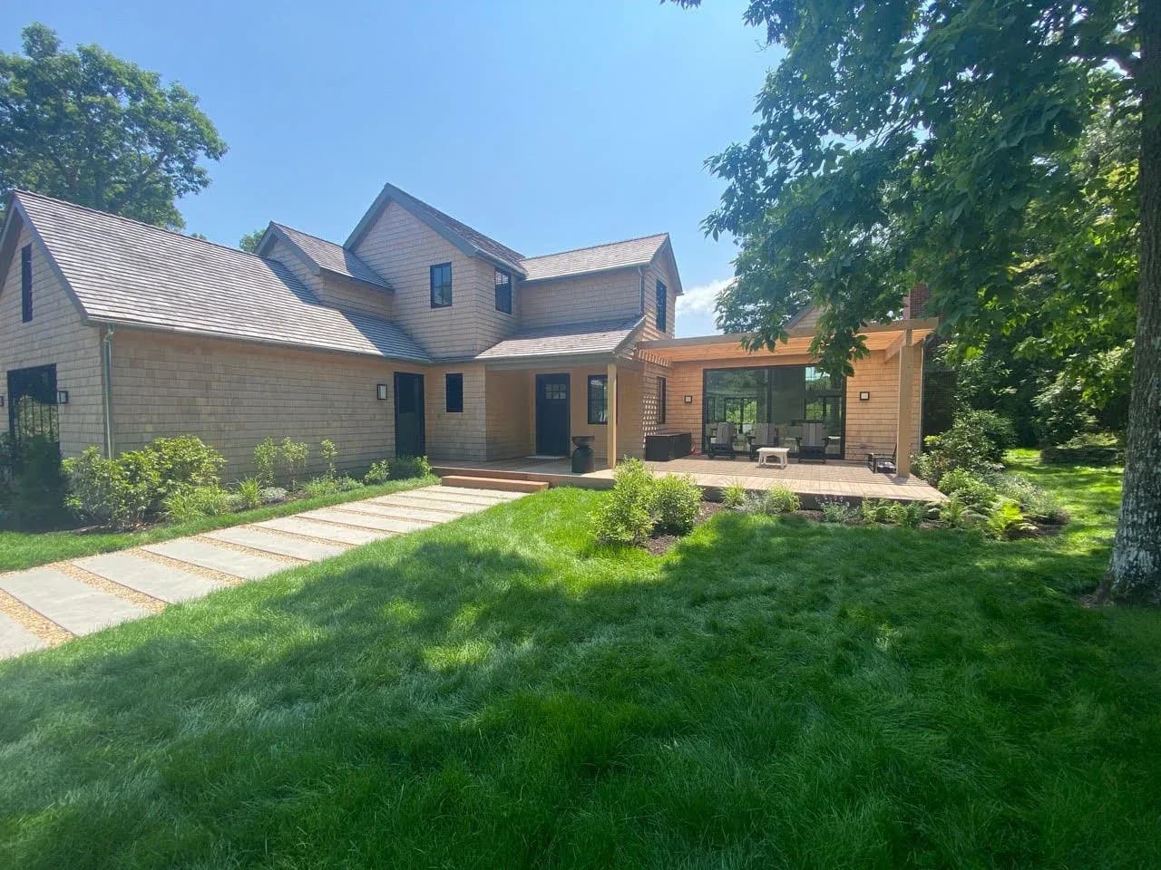 Modern residential architecture with mixed materials including stone and wood siding, featuring a geometric facade and manicured lawn with stone pathway by Jonathan B. Held A.I.A. Architect.