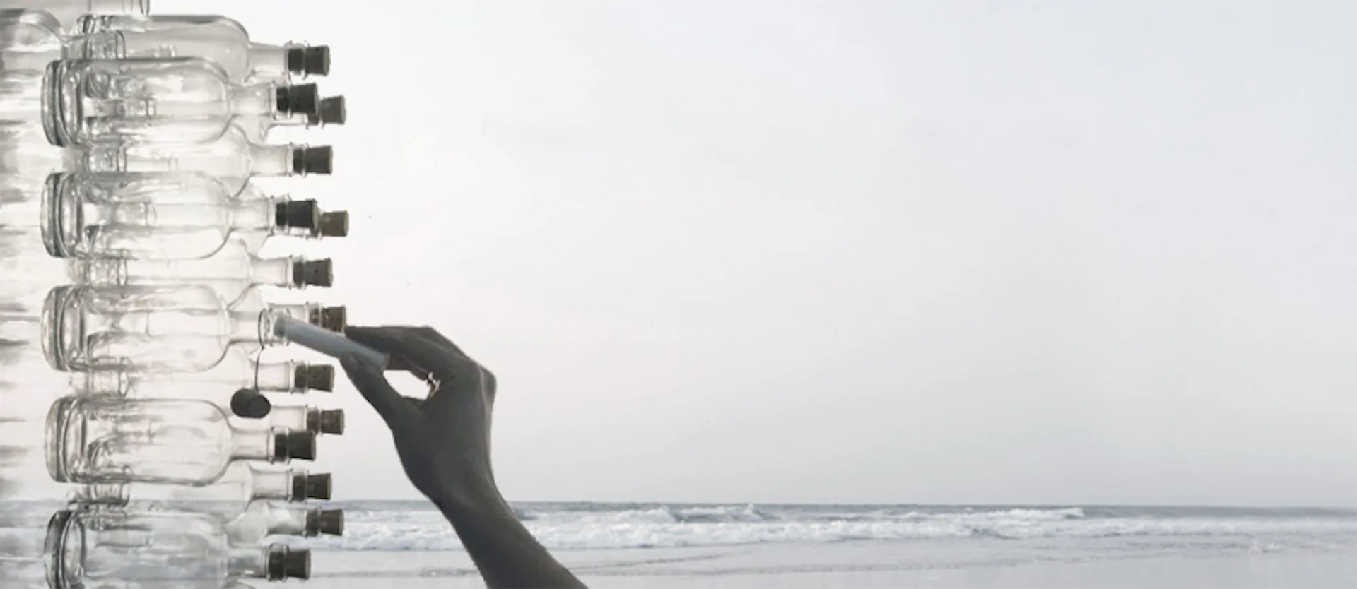 Hand adjusting modular wall-mounted components against an ocean horizon backdrop, demonstrating an interactive installation or product system by julian king architect.