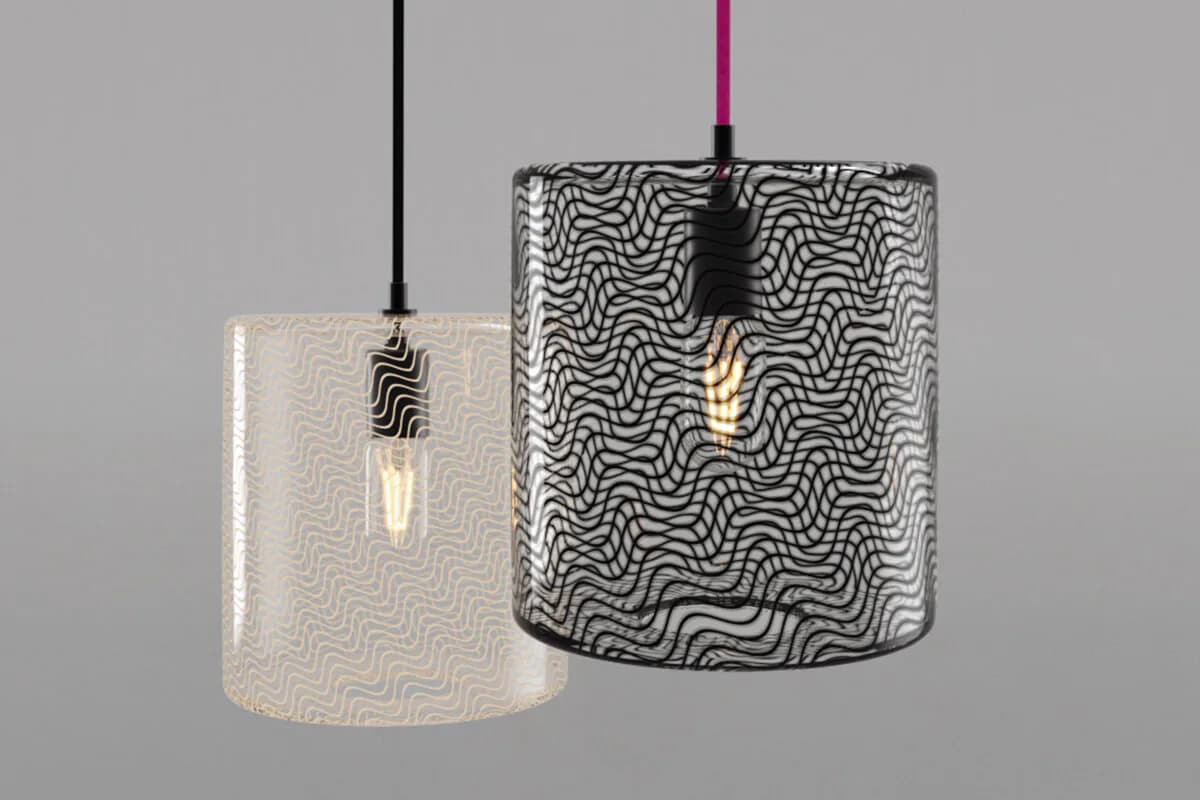 Three cylindrical pendant lights with geometric wave-pattern fabric shades in cream and black, suspended from thin cables against neutral gray background by KEEP.