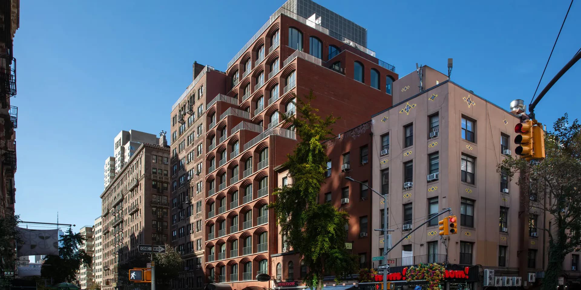 Red brick residential buildings with classical architectural detailing line a sunny urban street, designed by Kohn Pedersen Fox.