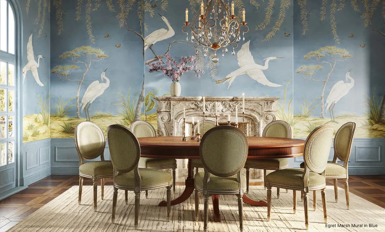Dining room with blue-grey walls featuring chinoiserie mural with cranes and trees, round wooden table, upholstered chairs, crystal chandelier, and parquet flooring by Kravet Inc.