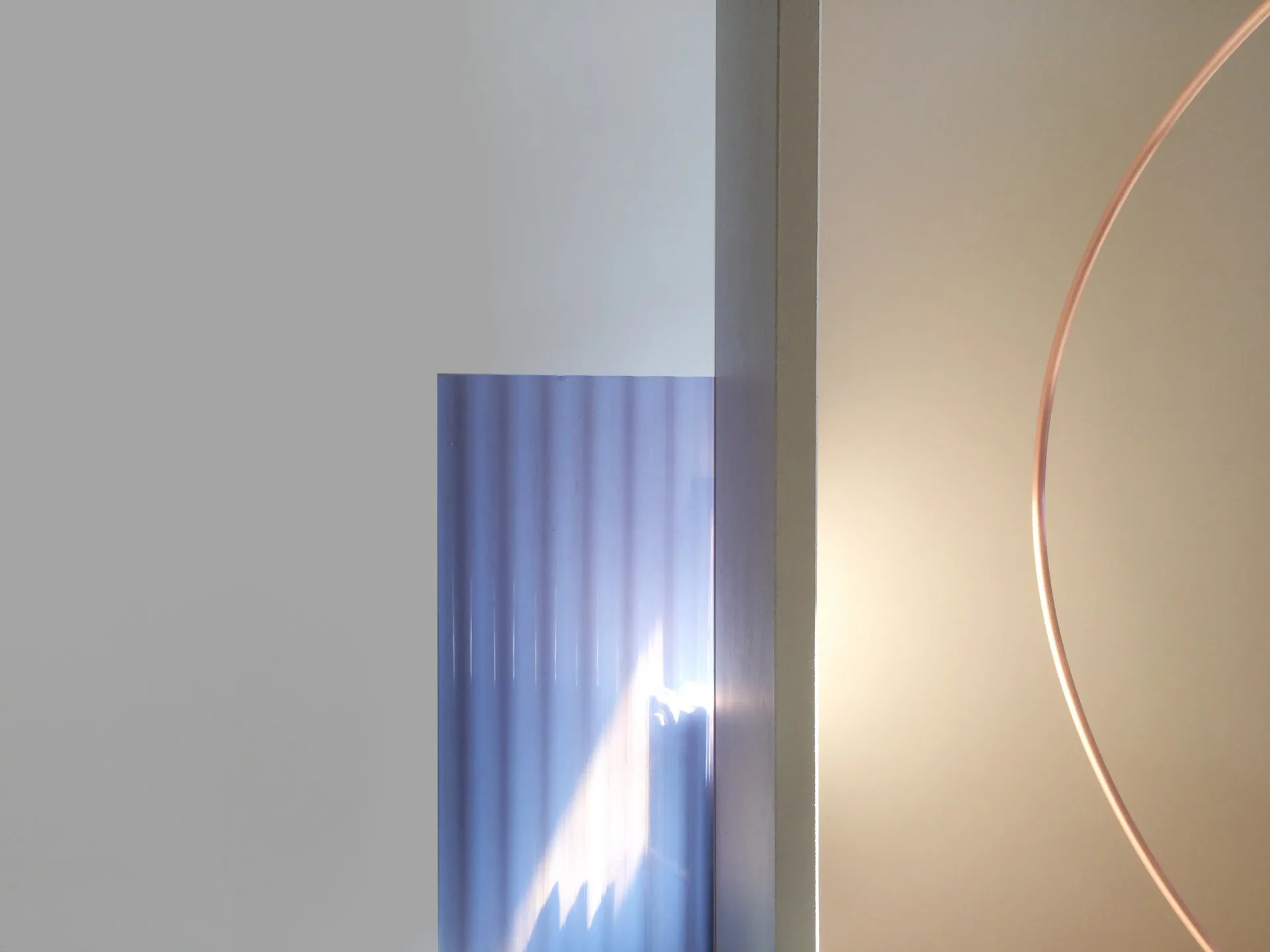 Minimalist interior with vertical ribbed blue-gray panel, white walls, and curved neon lighting element by Ladies & Gentlemen Studio.