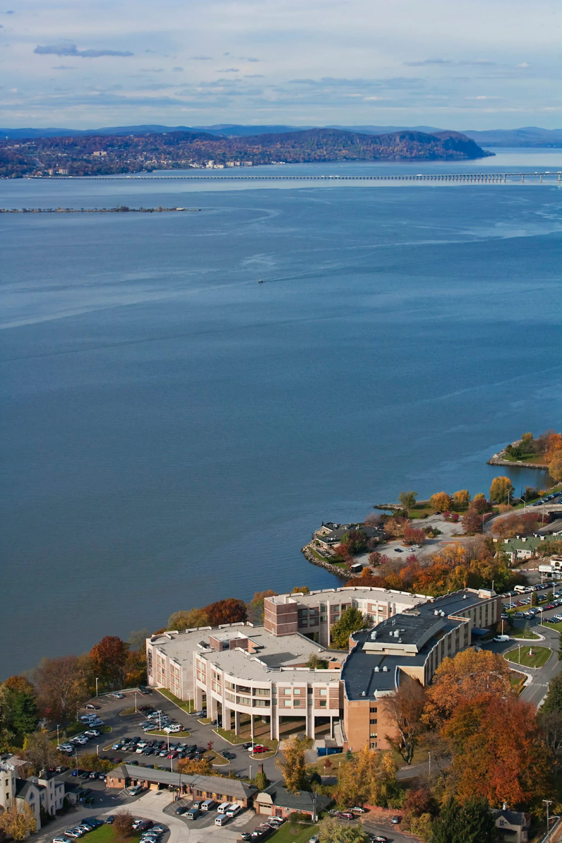 Waterfront institutional building with curved modern architecture overlooking a bay, surrounded by autumn foliage and parking areas, by Landow and Landow Architects AIA.