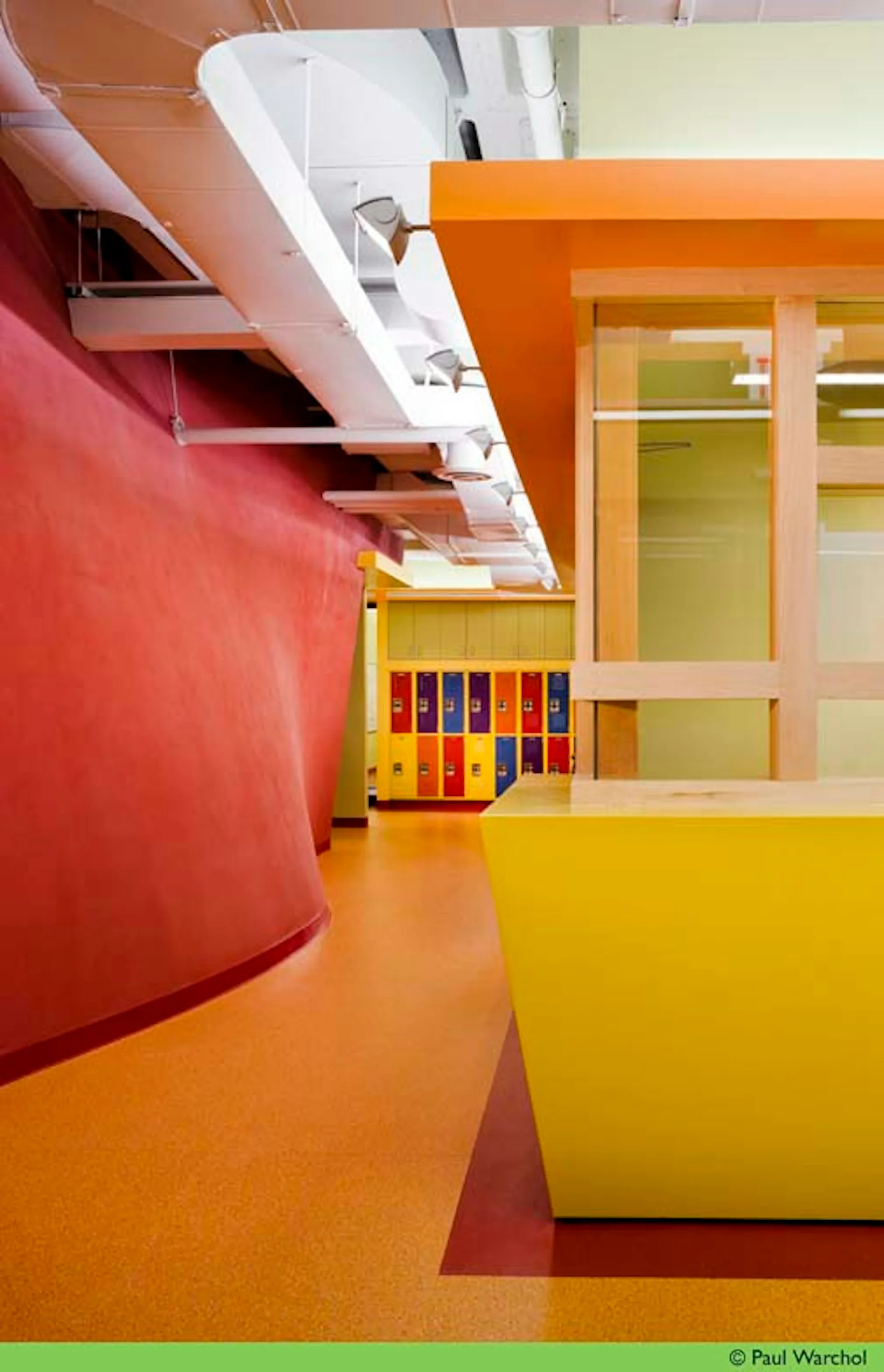 Vibrant interior space with curved red and orange walls, yellow floor, and natural lighting from skylights, featuring modern architectural design by Landow and Landow Architects AIA.