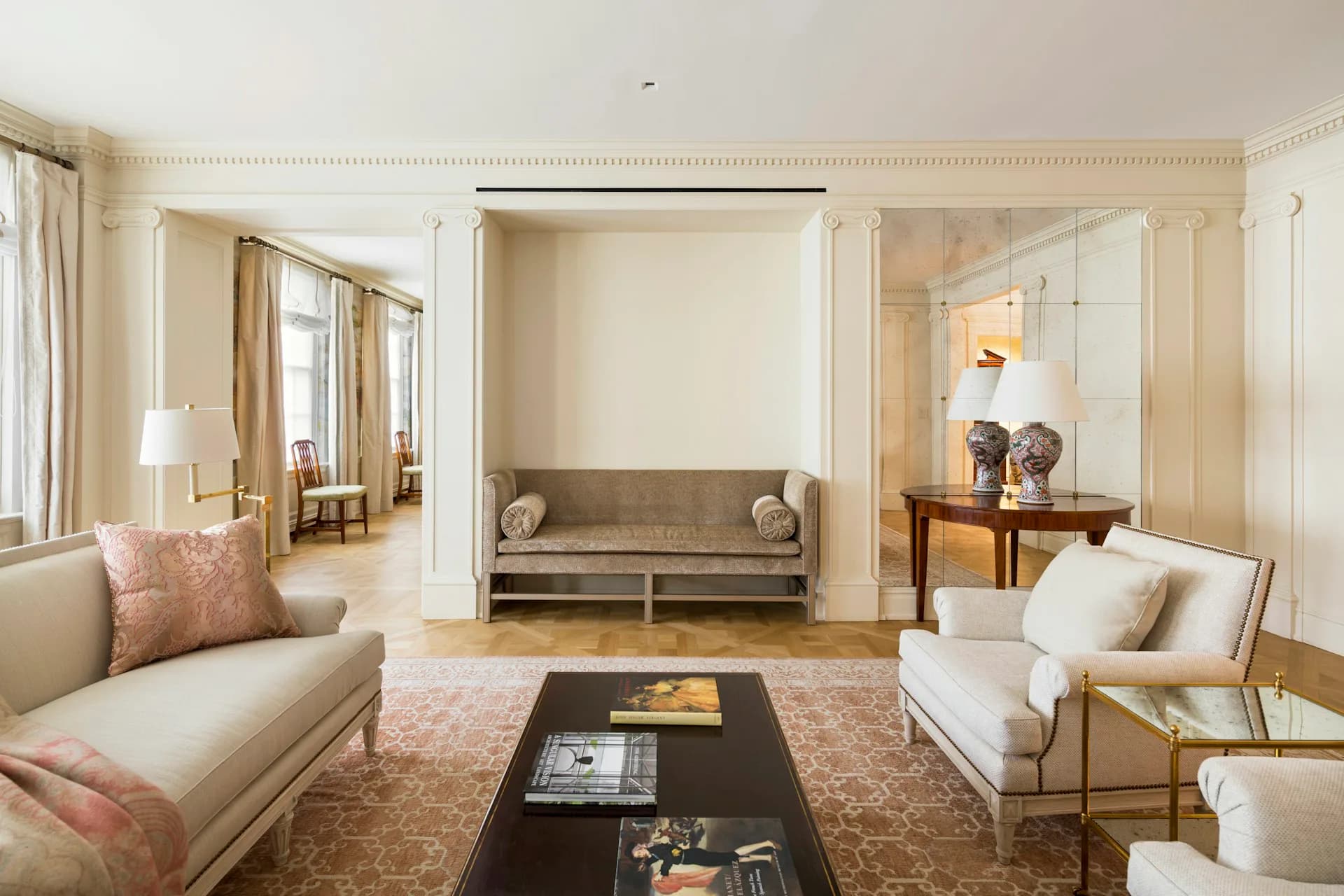 Elegant residential living room with cream and taupe palette, featuring built-in alcove seating, symmetrical cream upholstered chairs, and sophisticated lighting by Larson Architecture Works pllc.