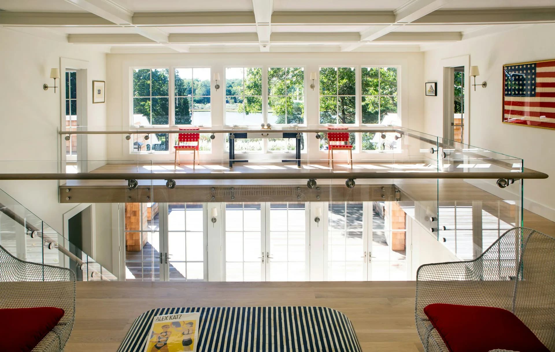 Modern two-story loft interior with open floor plan, steel railings, exposed beams, large windows, red accents, and American flag artwork by Larson Architecture Works pllc.