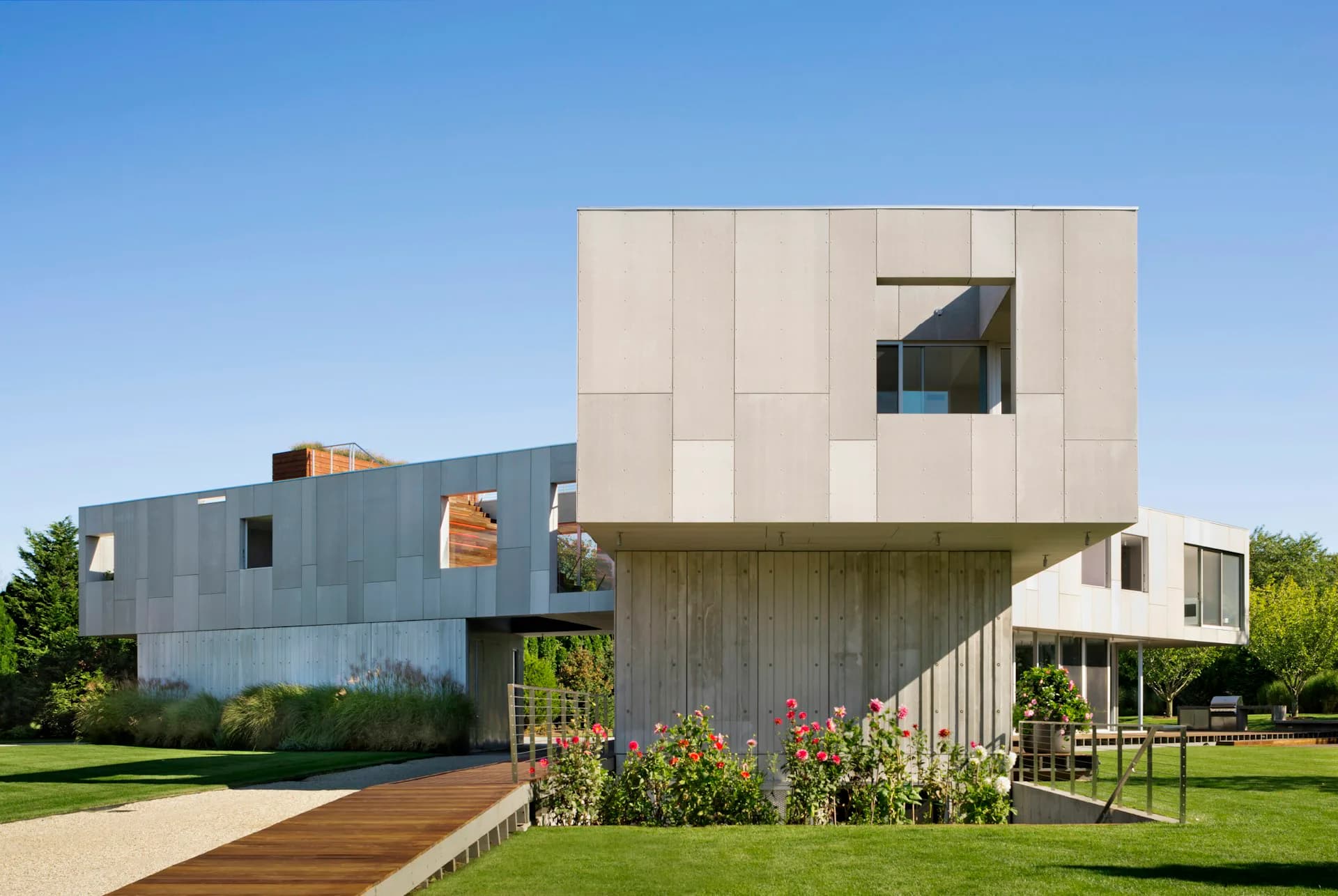 Contemporary residential architecture featuring stacked geometric volumes in cream and weathered wood, with a cantilever design and integrated landscape by LEVENBETTS.