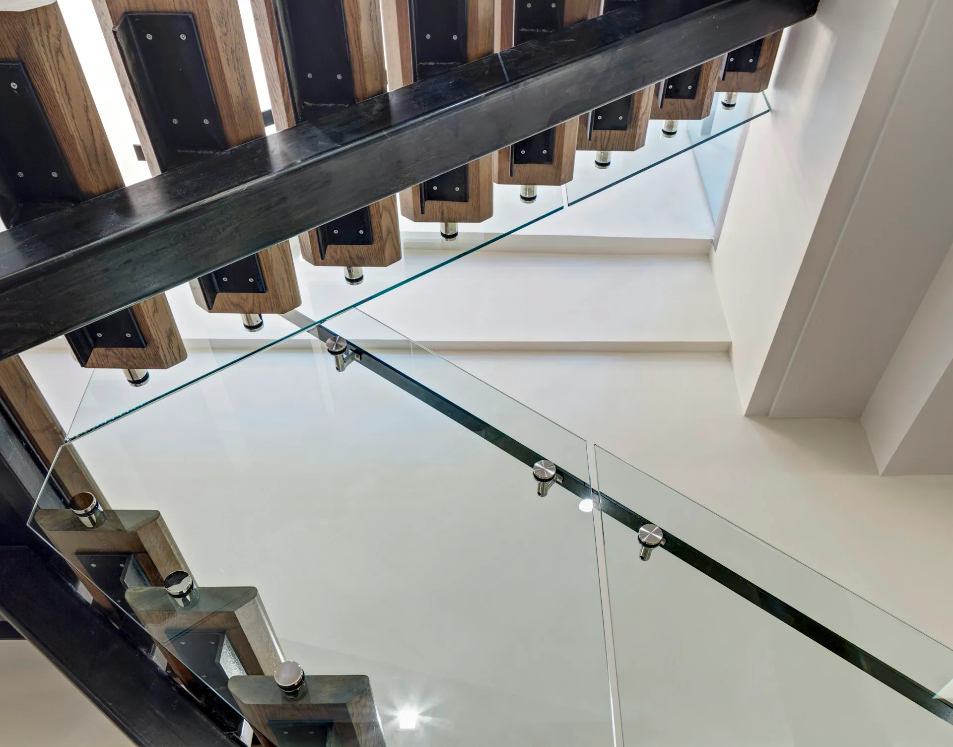 Modern stairwell with glass railings, wooden treads, and minimalist design featuring clean lines and neutral palette by Lilian H. Weinreich Architects.
