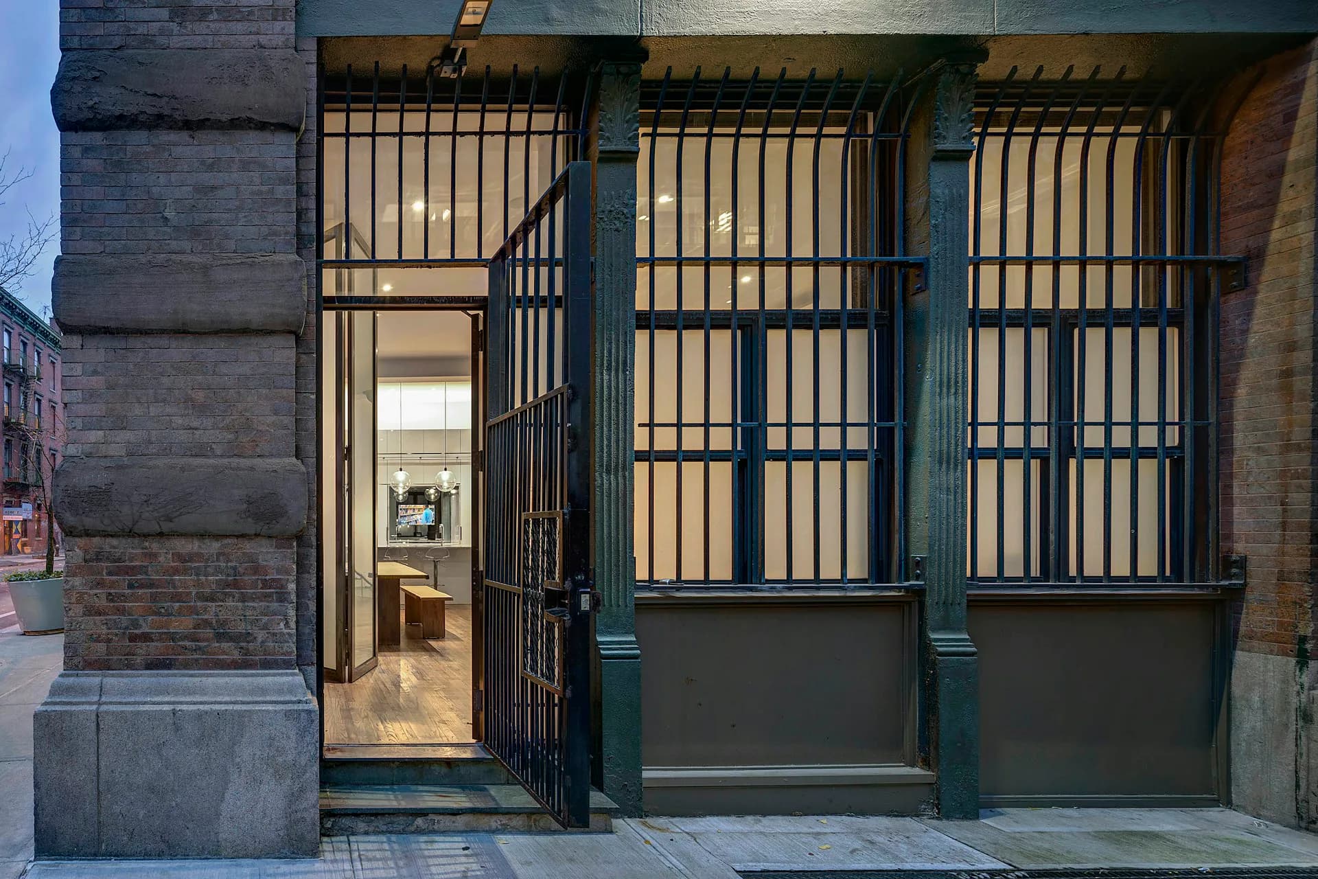 Contemporary storefront entrance featuring dark green steel framing with vertical bars, glazed door, and minimalist facade by Lilian H. Weinreich Architects.