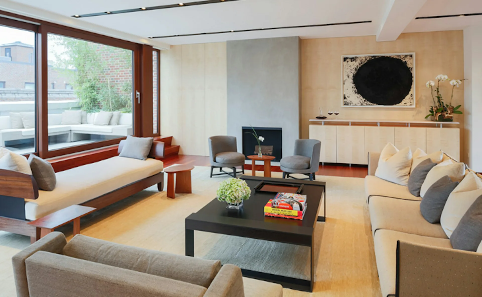 Modern living room with warm wood tones, built-in window seating, fireplace, neutral furnishings, and dark accents designed by Lisa Dubin Architect.