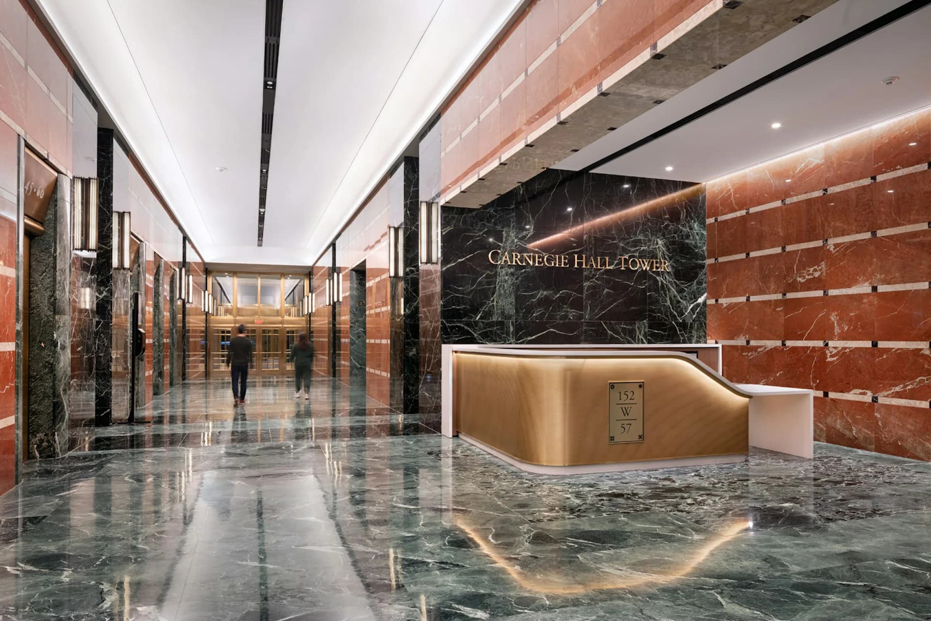 Modern lobby interior with polished green marble flooring, copper-toned accent wall, and sleek reception desk featuring illuminated signage, designed by Loci Architecture PLLC.