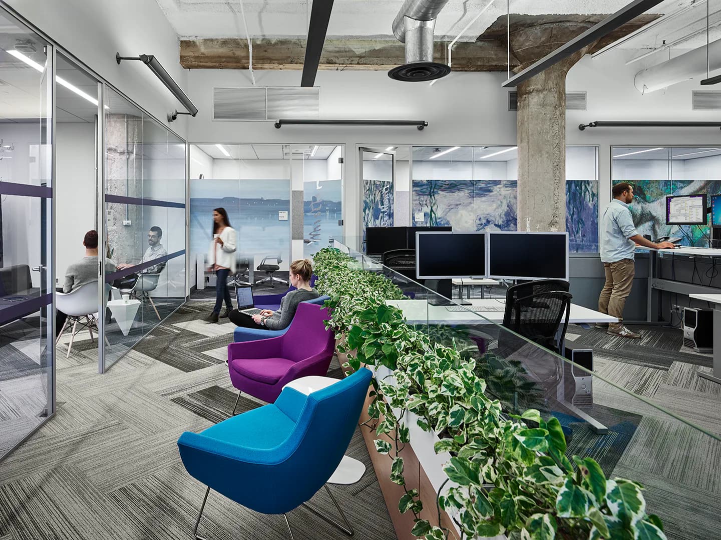 Modern office interior featuring colorful lounge seating, planted greenery, glass partitions, and open workspace with natural light by Lumen Architecture.