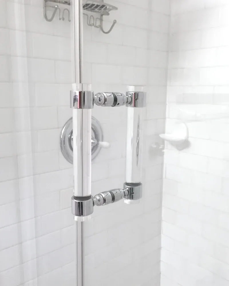 Minimalist bathroom shower enclosure with chrome hardware, white subway tile walls, and glass door featuring clean linear details by LuxHoldUps.
