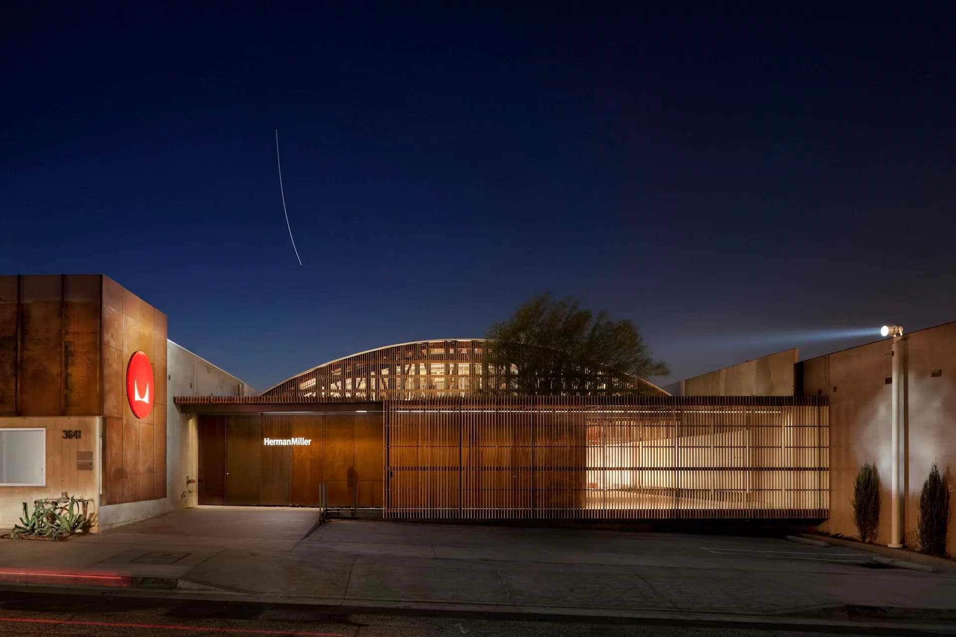 Nighttime architectural rendering of a modern residential gateway with warm-toned metal screens, illuminated signage, and landscaping by LYNCH EISINGER DESIGN Architects.
