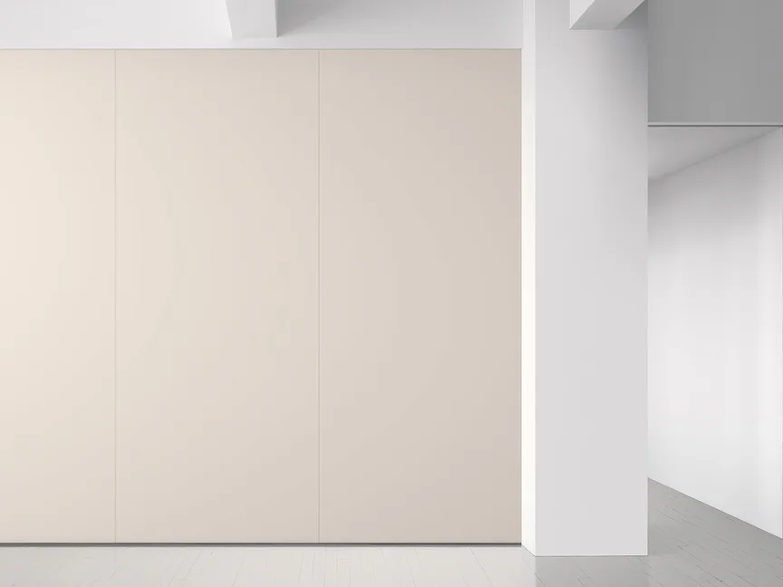 Minimalist interior space with cream-colored paneled wall and white architectural elements, clean geometric composition by Maharam.