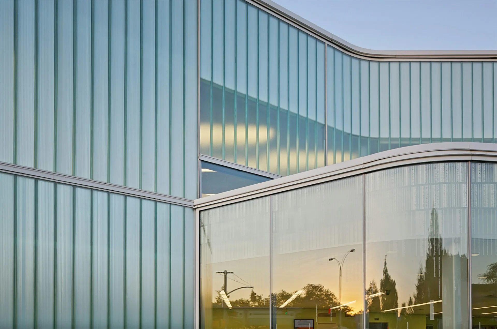 Modern glass and metal-clad building exterior with reflective windows capturing landscape views, designed by Marble Fairbanks.