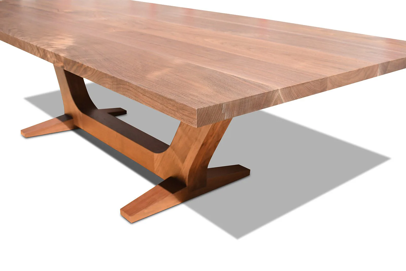 Wooden dining table with sculptural trestle base and natural wood finish, rendered with soft shadows and neutral background by Mark Jupiter.