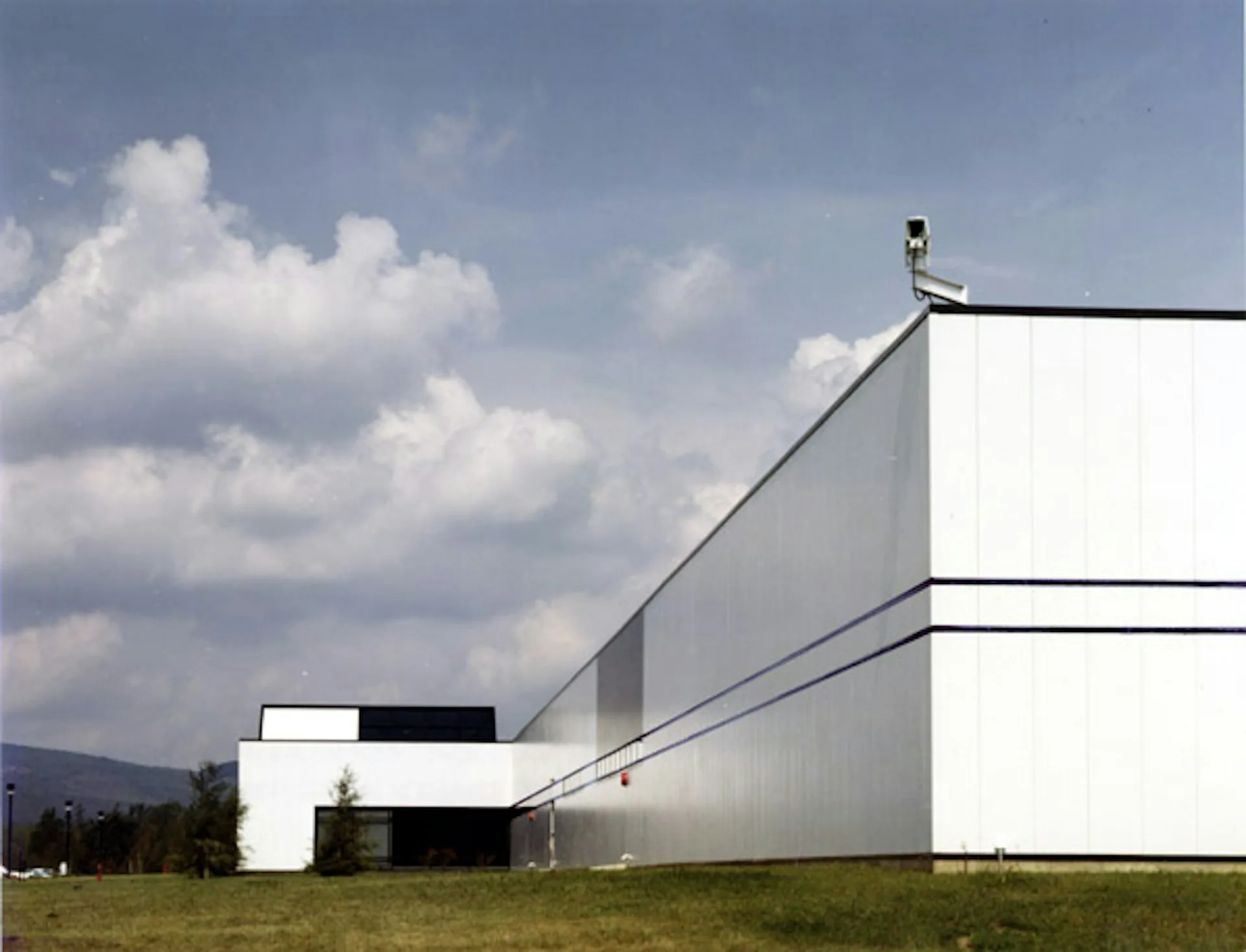 Modernist white building with clean geometric forms set against mountains and cloudy sky, designed by martin holub architects.