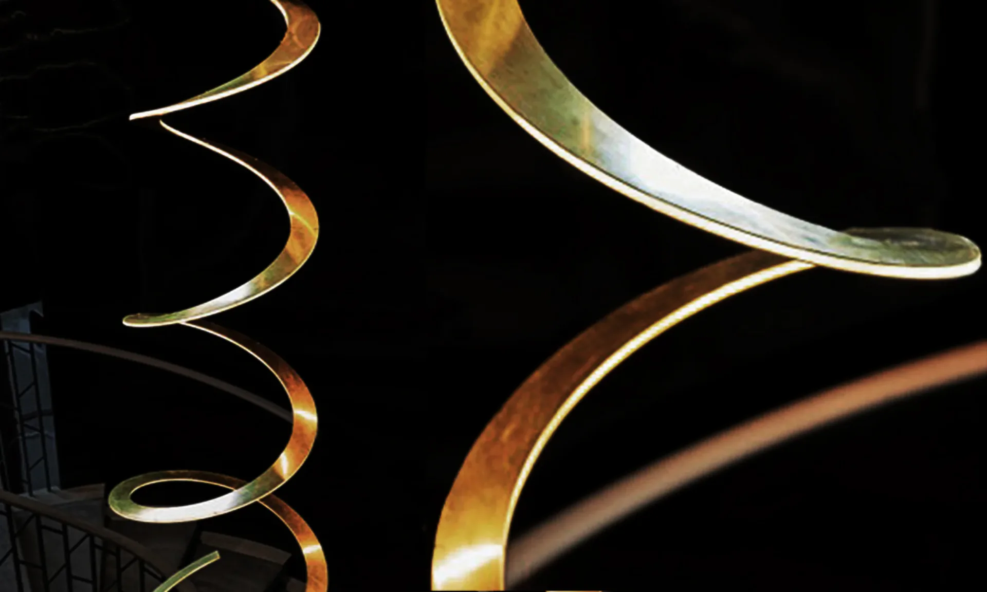 Curved metalwork details in brass and steel with warm gold and silvery finishes, showcasing elegant fabricated metal components by MASTER Architectural Fabrication.