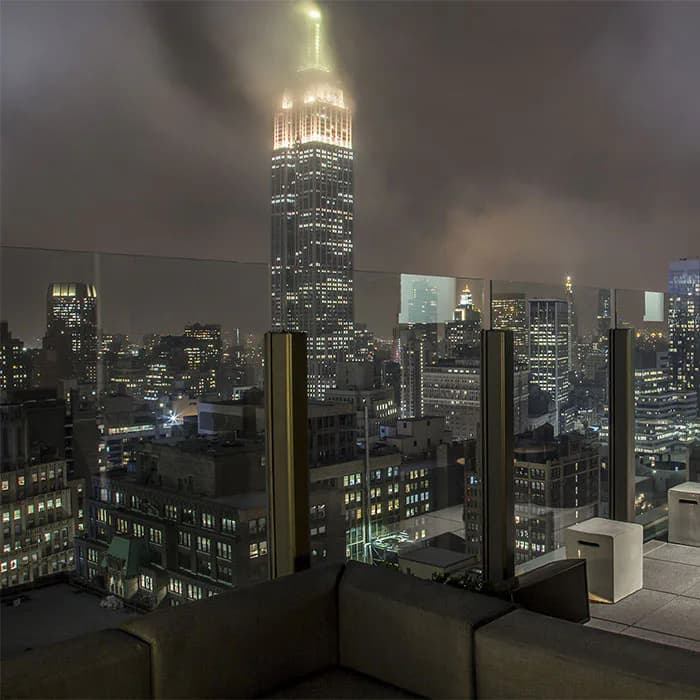 High-rise residential interior with floor-to-ceiling windows framing the illuminated Empire State Building and Manhattan skyline at night by McKay Architecture/Design.