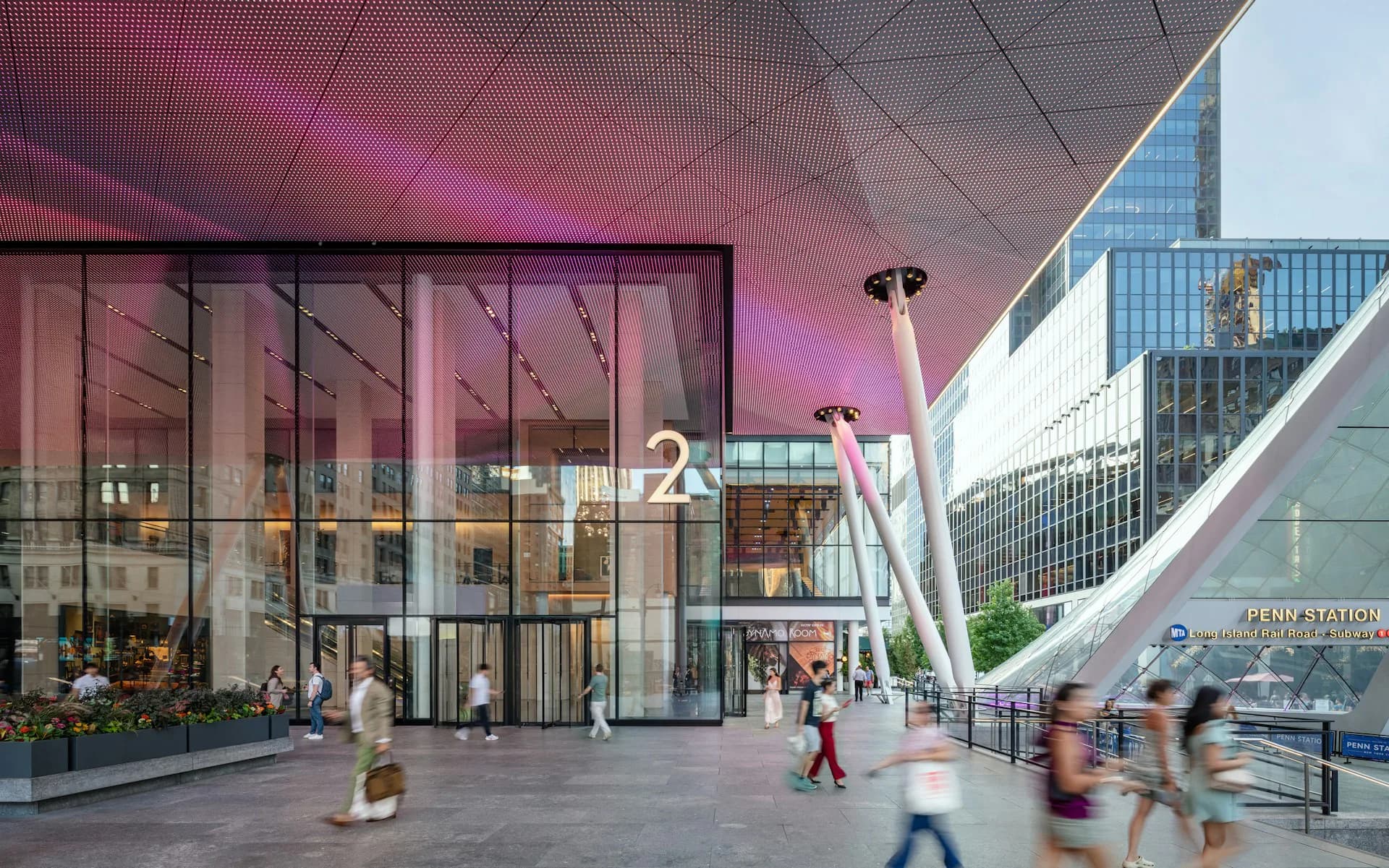 Modern public plaza with pink-purple ceiling, glass storefronts, and curved architectural elements by MdeAS Architects.